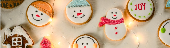 christmas cookies with snowman faces and the word JOY in one cookie