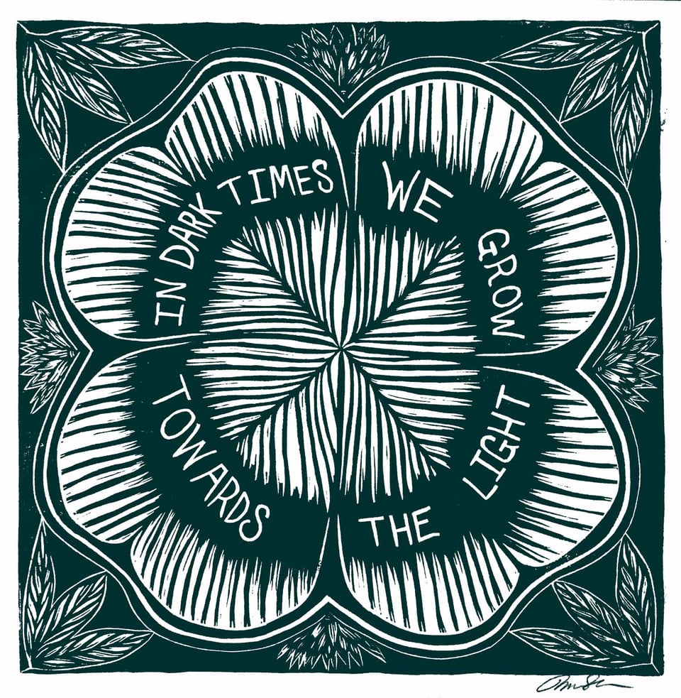 A print of a flower with the text "In dark times we grow towards the light"