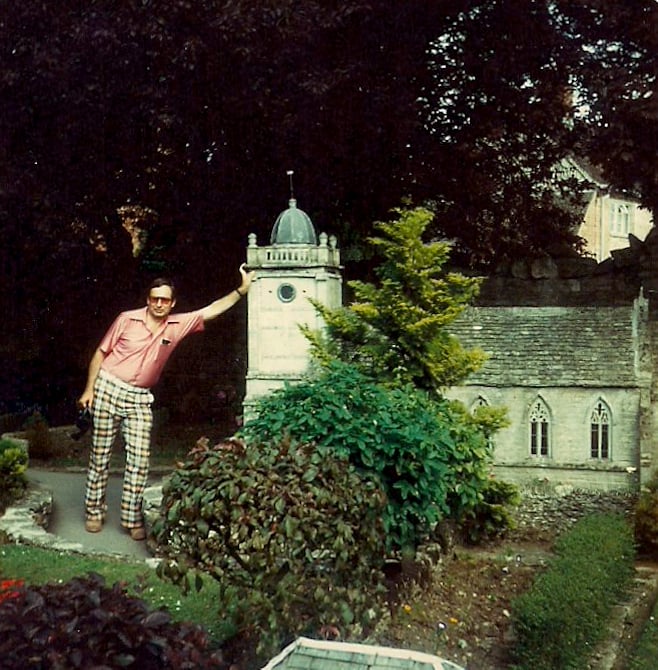 Man in very loud plaid pants and pink shirt leaning on model St. Paul's Cathedral in London, 1980