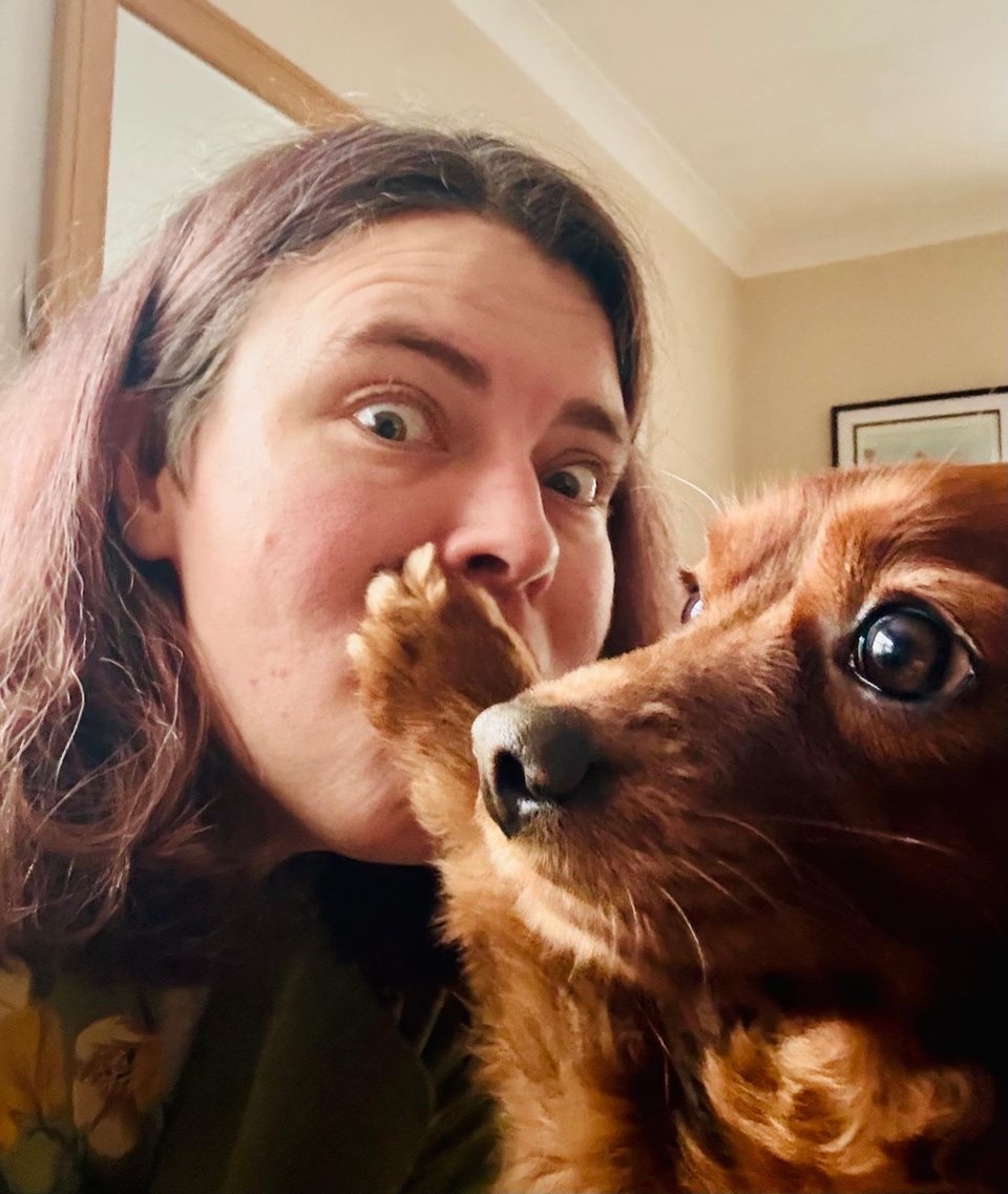 A cute dog places his paw on a beautiful woman's mouth.