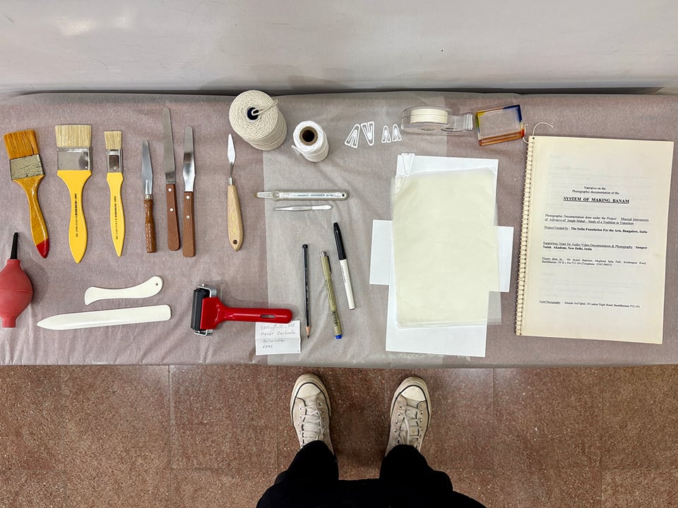 A top down view of tools and implements used in a multimedia archive for the preservation of archival objects. The tools are all arranged on a table in their respective groups and within uniquely identifying juxtapositions.