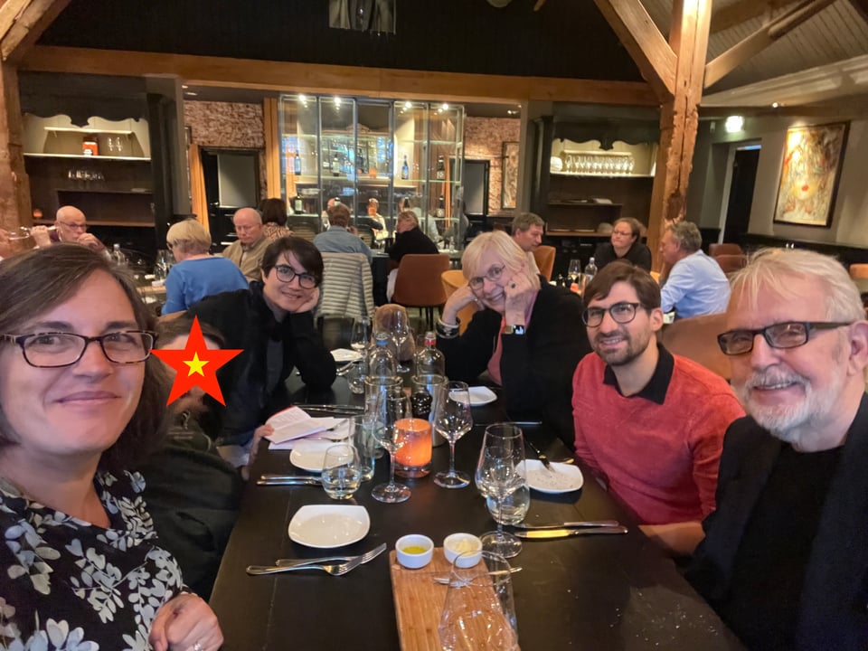 Six people around a dining table look at the camera. There is a child with a star over his face for privacy.