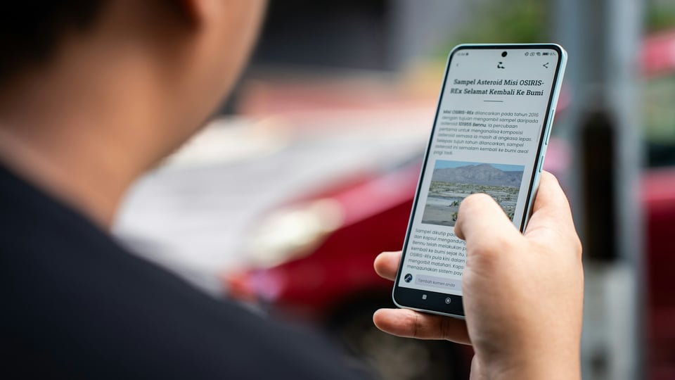 Looking over the shoulder of a person who is reading news on a phone. Photo by Amanz on Unsplash