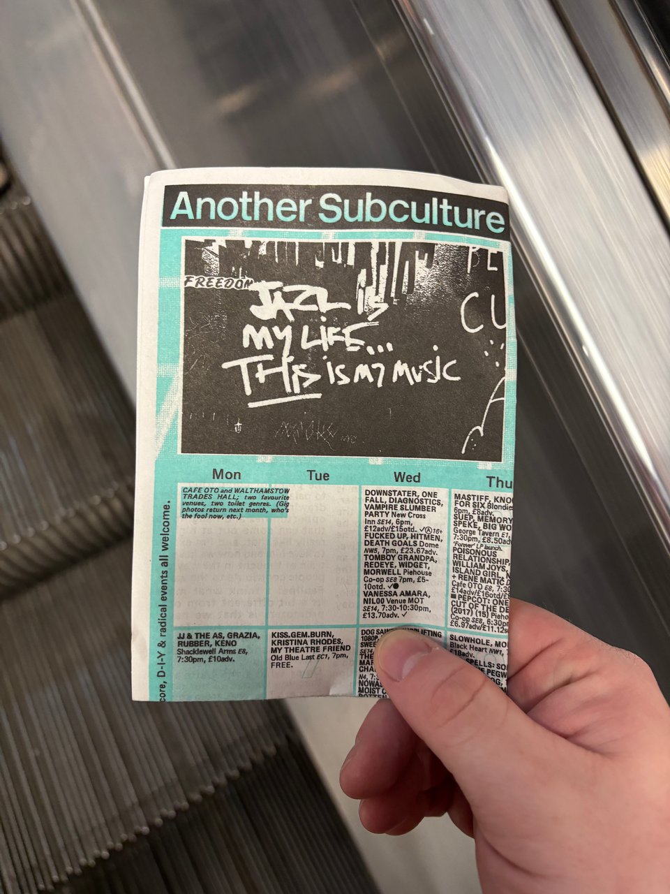 a hand holding a magazine on an escalator