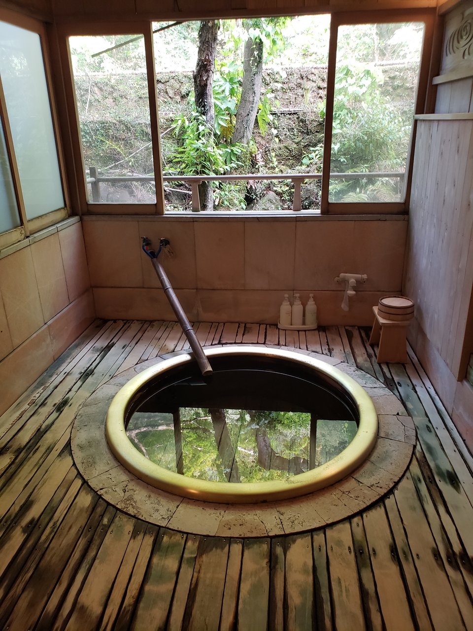 A round wooden onsen bath open to the air.
