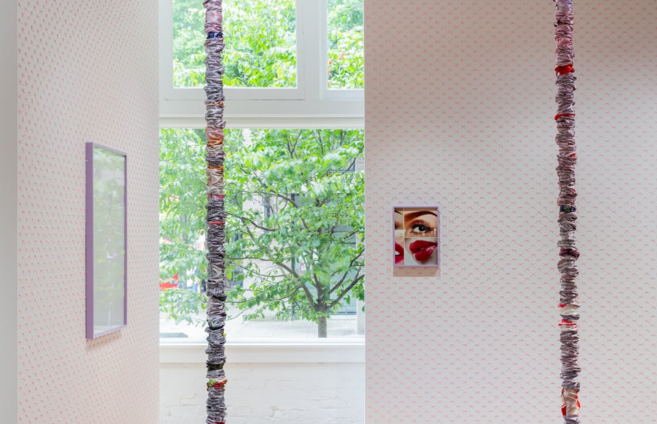 an art gallery featuring framed photographs and two tall thin fabric sculptures