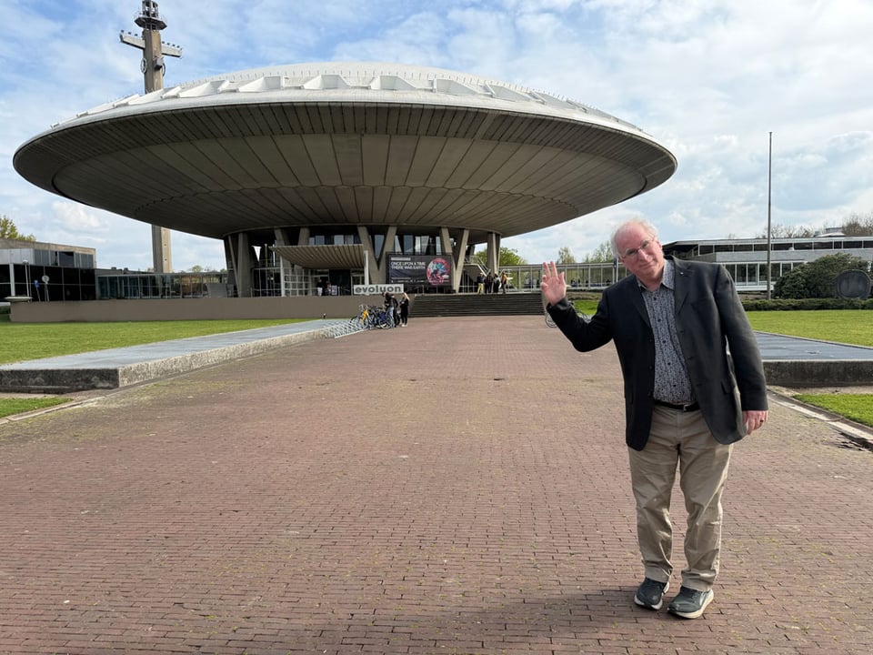 A man stands in front of a museum in Eindhoven in the Netherlands which is shaped like a large circular UFO.