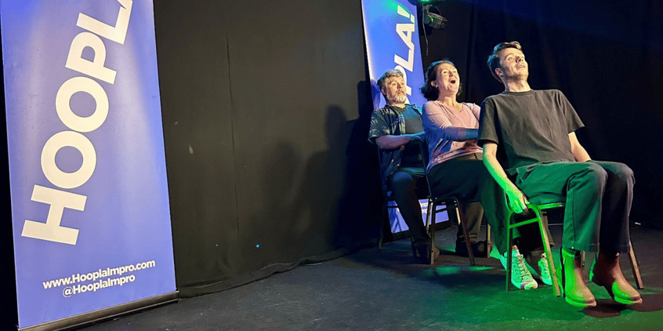Three improvisers on a stage pretending to be on a rollercoaster.