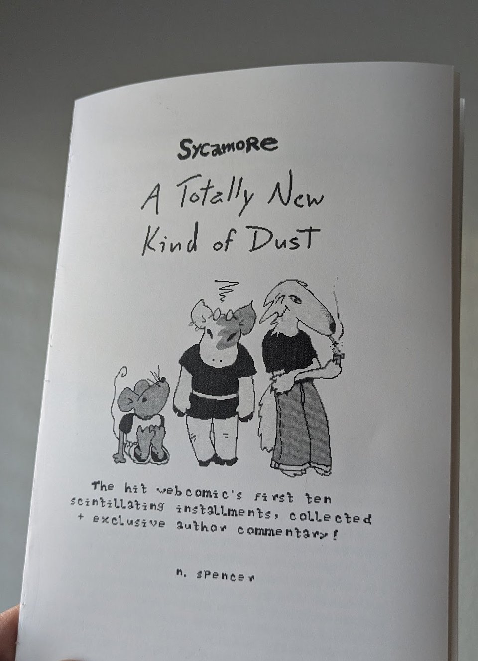 the cover of a zine reads "Sycamore; A Totally New Kind of Dust; The hit webcomic's first ten scintillating installments, collected + exclusive author commentary!; n. spencer" there is also an illustration of Gingham, Amy, and Nina from Sycamore