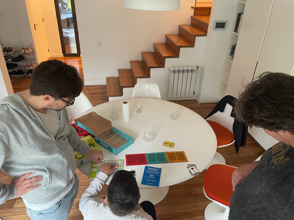 Two men and a boy explore a robot programming board game.