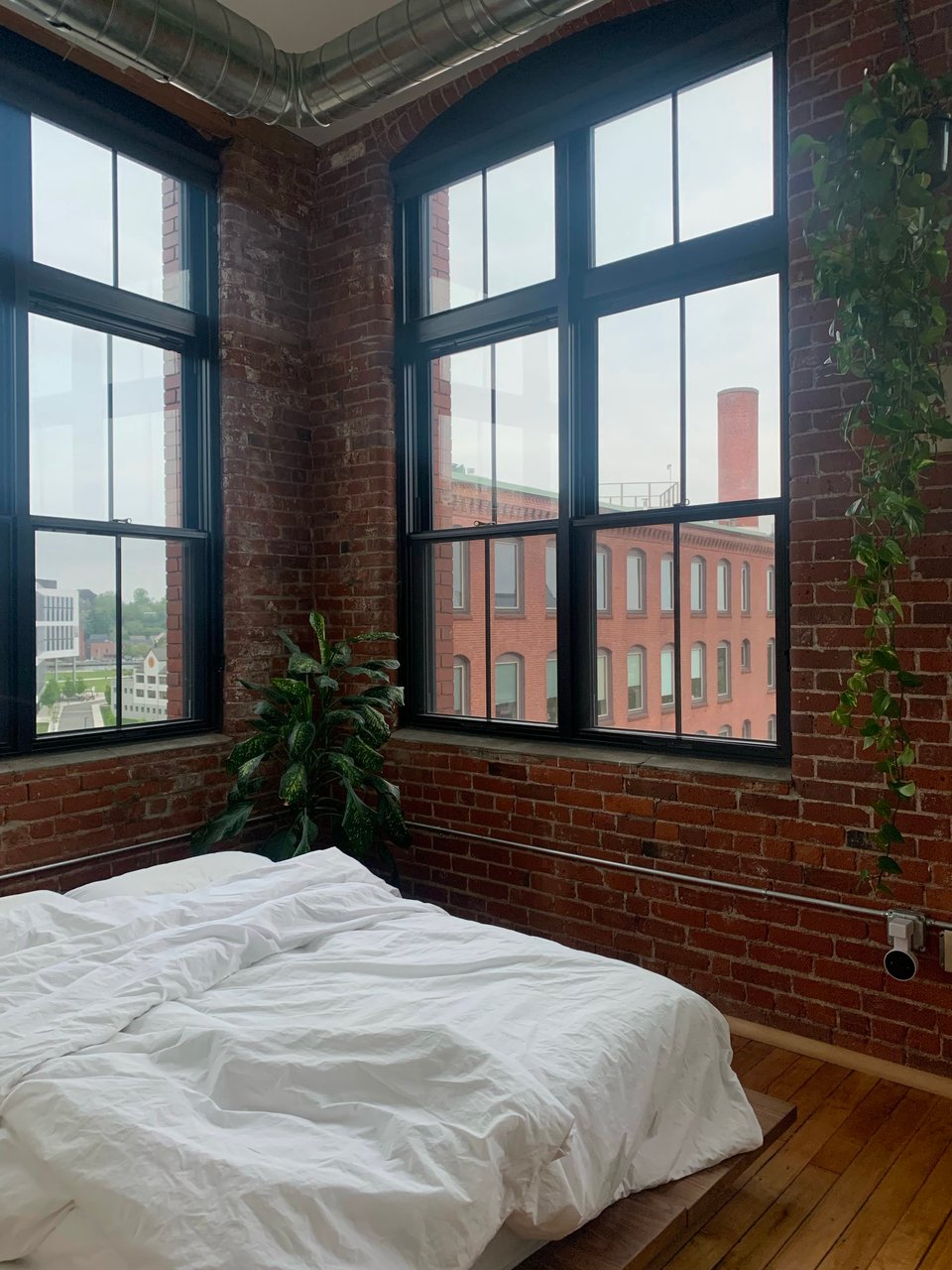 A bedroom with exposed brick walls and large windows