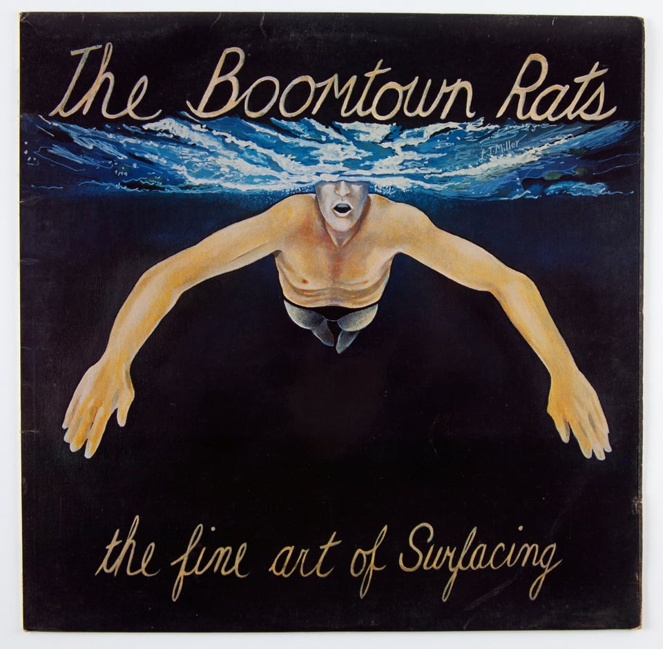 The album cover for The Fine Art of Surfacing by The Boomtown Rats. There is an image of a man swimming. Most of his body is under water. We can see his mouth and nose, but not his eyes or the top of his head, which are above the surface.