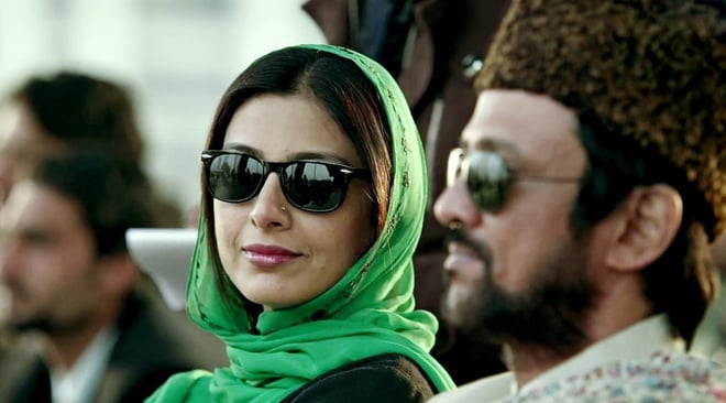 Tabu in Haider wearing sunglasses, sitting with another character from the movie looking right at the camera.