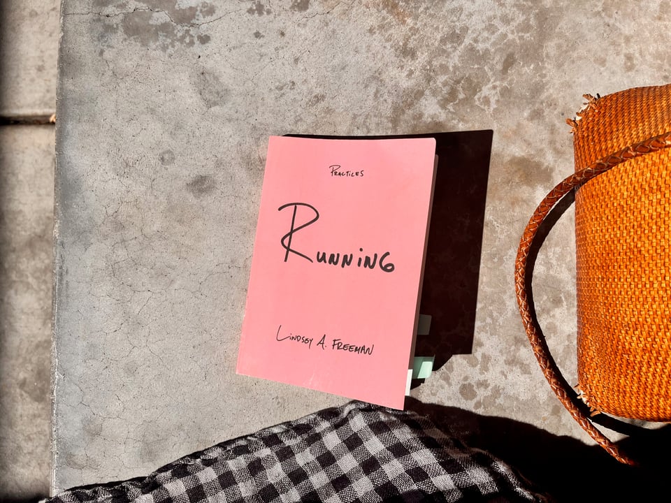 the book Running by Lindsey A Freeman sitting on a concrete bench