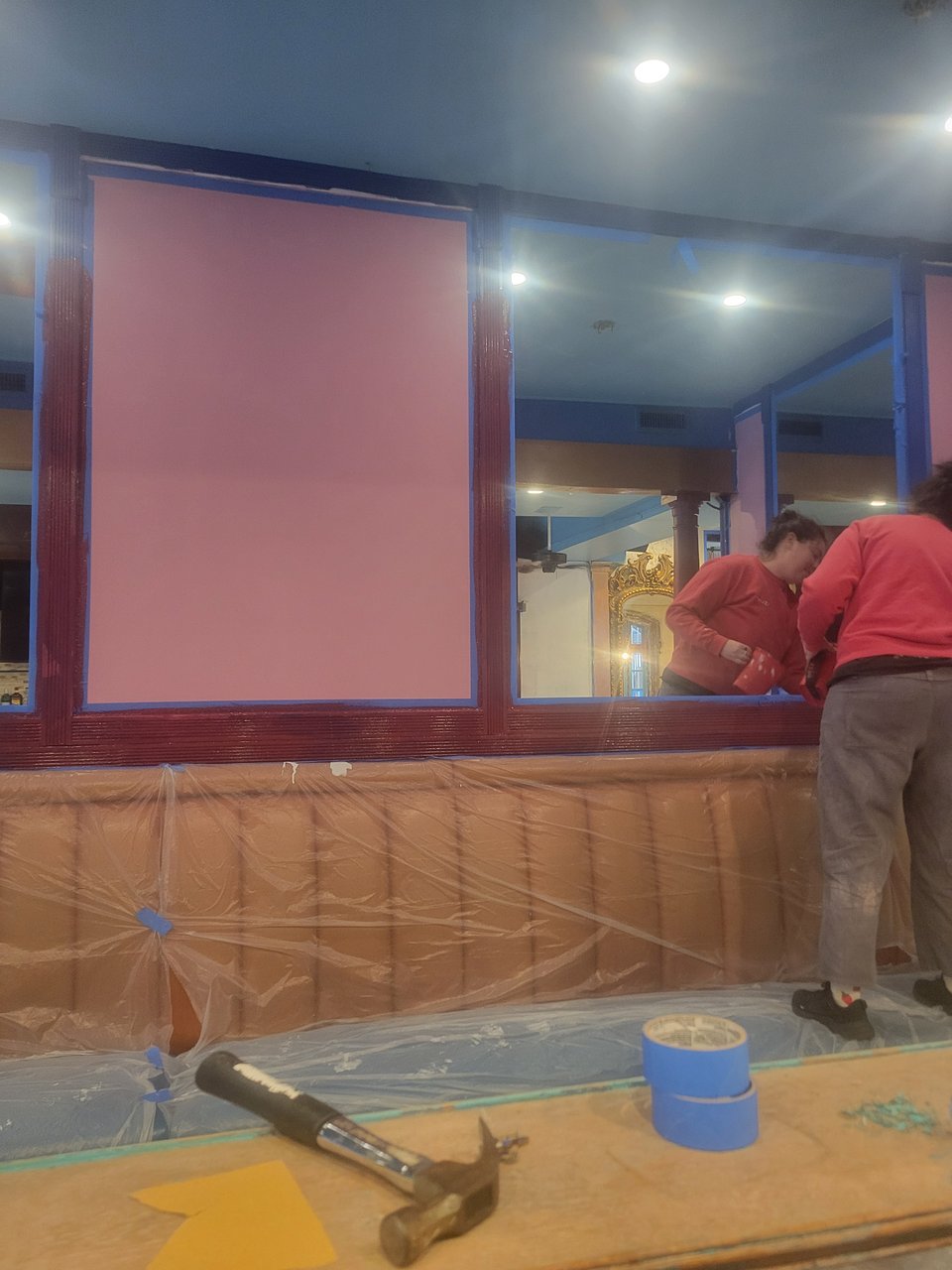 Co-owner Julia painting the gallery section of the bar, panels are pink with red trim.