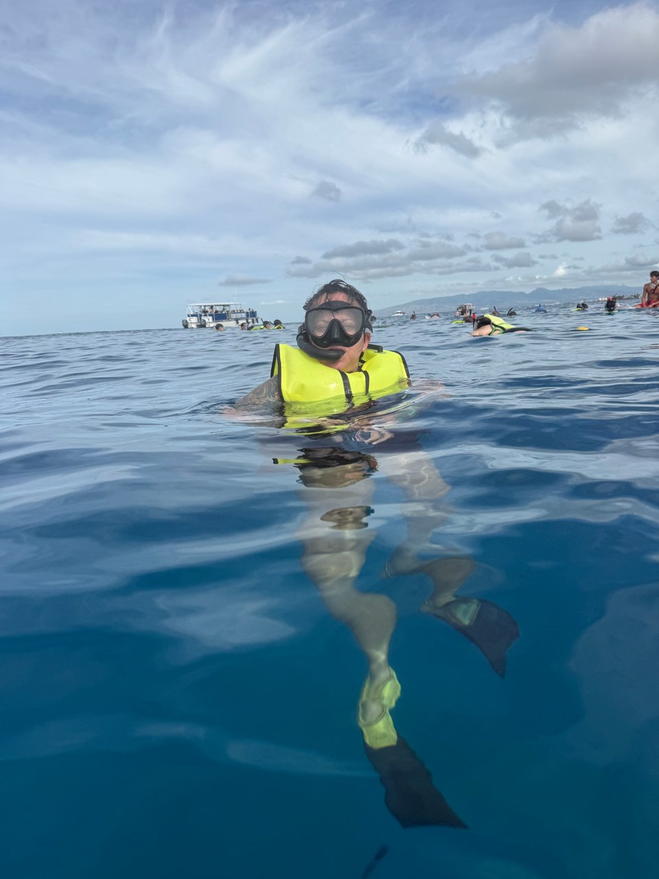 Wendy in snorkeling mask and fins in the open ocean off the coast of Waikiki. Several other snorkelers and a boat are in the background.