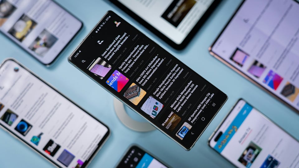 Several mobile phones, open to news apps. One phone in the center is legible and clear; the rest are blurry. Photo by Amanz on Unsplash.