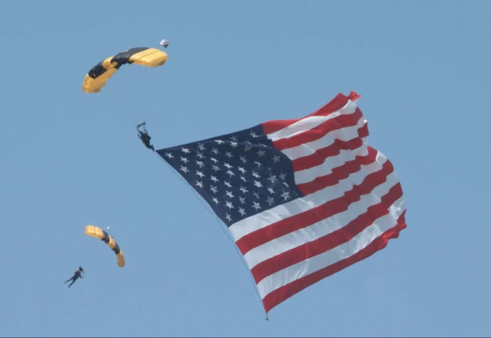 Two Golden Knights humbers with a large American Flag jumping over Washington D.C. on July 4, 2026.