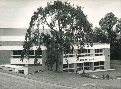 Black and white photo of Johnson Hall. It's a two storey building with ribbon windows across the front. It looks like it was a concrete frame with brick cladding. The signage is in classic 1970s Amigo No 1 font (or similar).