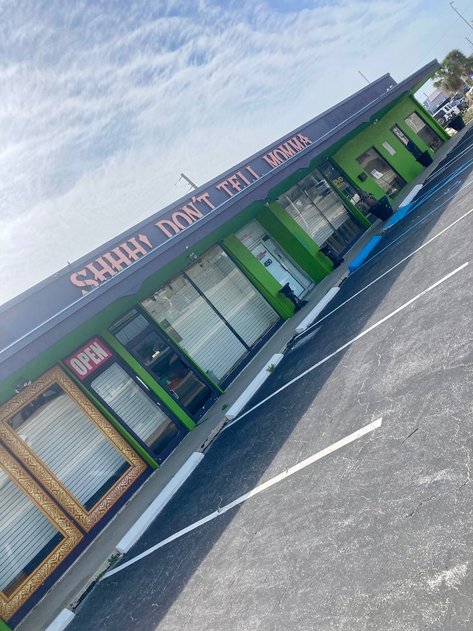 A strip mall store with a large sign reading SHHH! Don't Tell Momma.