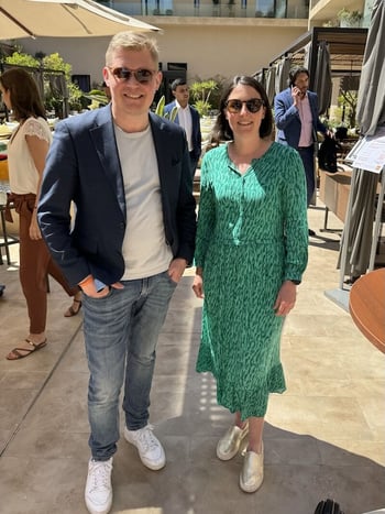 Photo of a man and woman posing in sunshine during a break at a business conference.