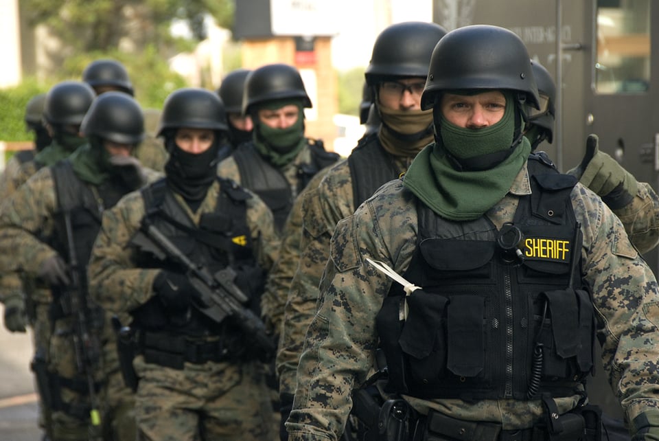 Cops in military camouflage, their faces covered, wearing helmets and carrying machine guns. They look like they're ready to invade a foreign nation.