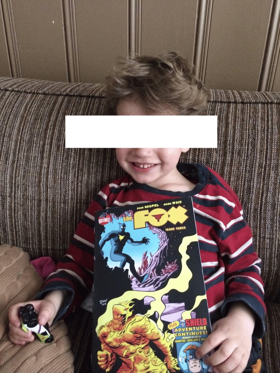 one of neil's kids holding a copy of the fox from archie comics, sitting on a sofa