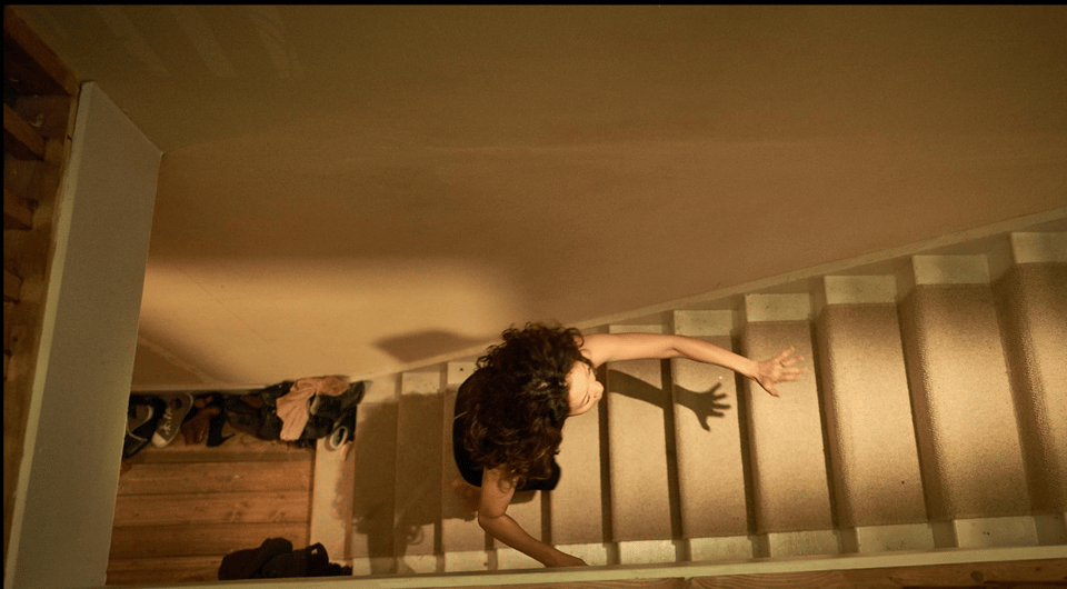 Overhead shot of Eve Polastri (from Killing Eve) running up household staircase at night
