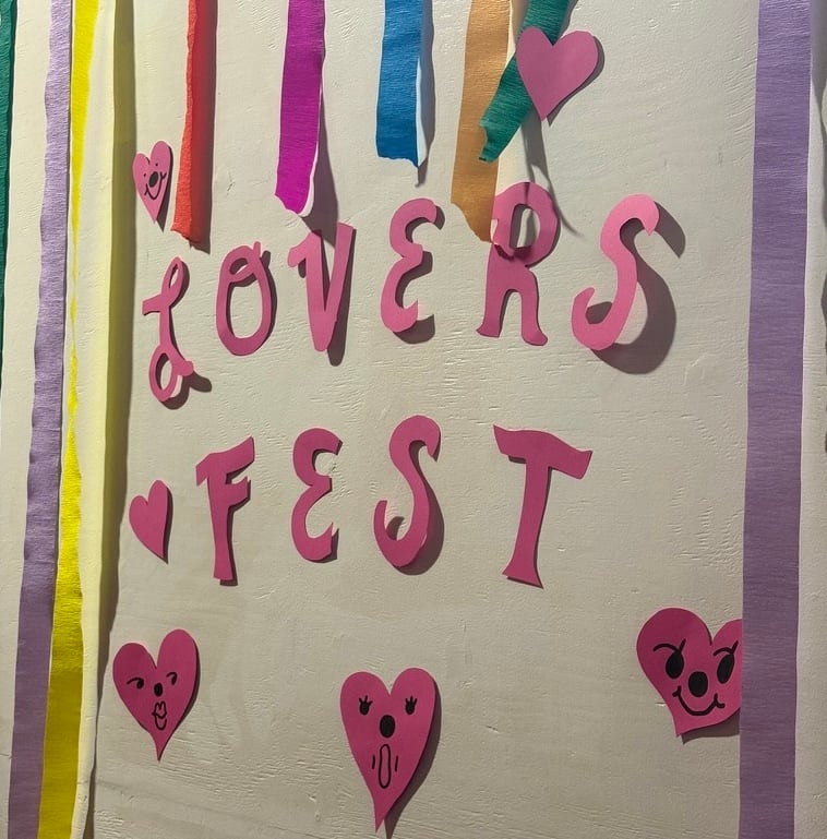 Cut out pink paper letters that read "Lovers Fest" with streamers and pink heart decorations that served as a welcoming sign to the show.