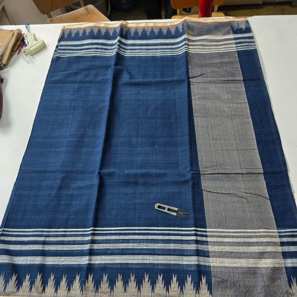 An indigo blue saree with a zari stripe pallu and zari kuppadam.