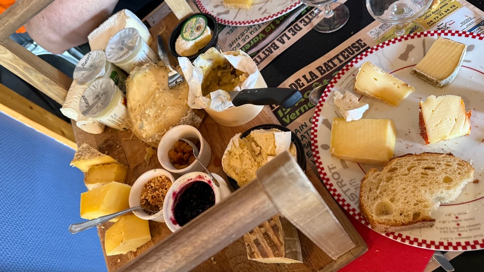 A luscious cheese platter with a plate next to it displaying a good sample of cheeses.