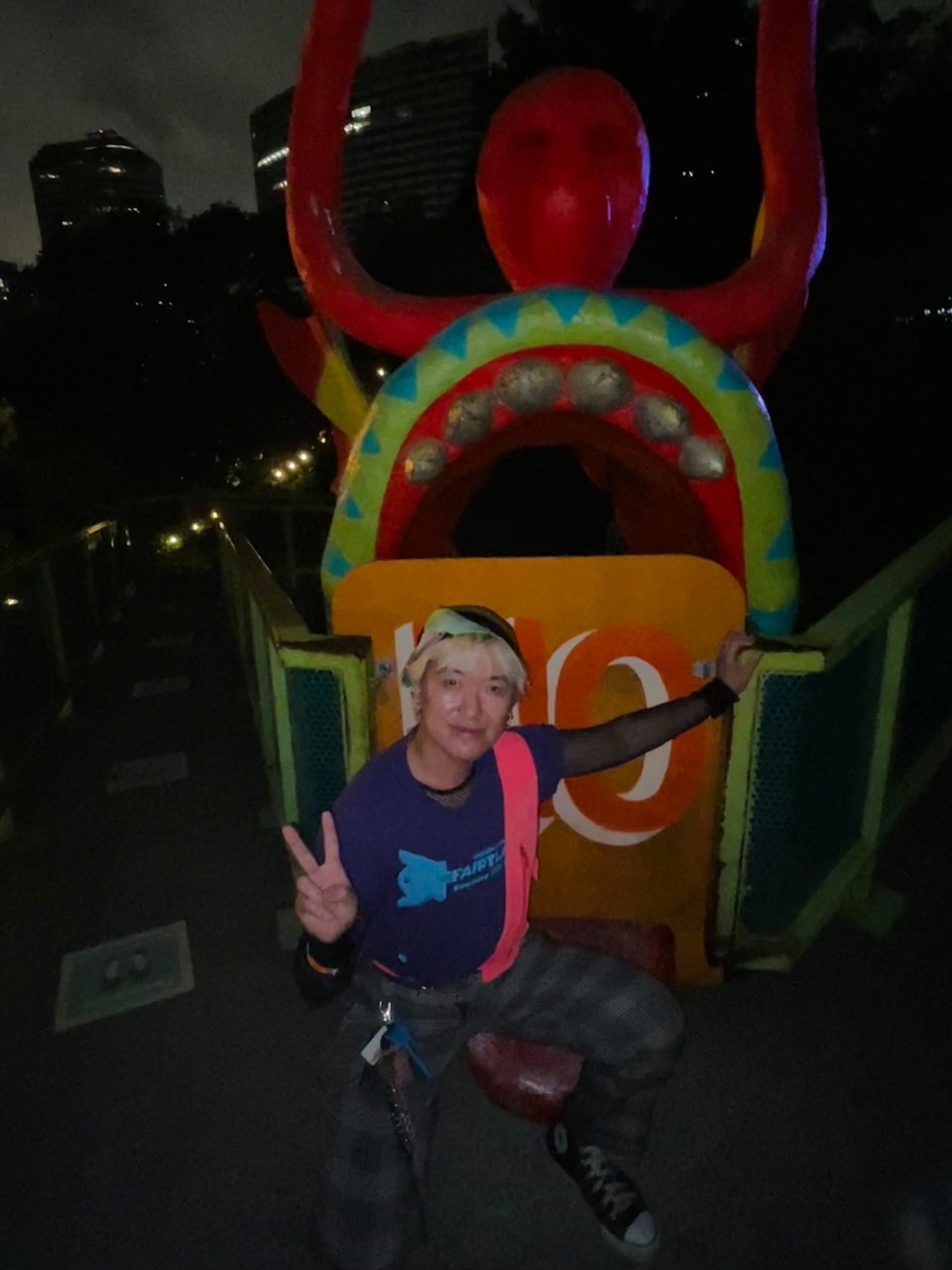 A photo of the writer Lio Min posing by the mouth of a slide shaped like a Chinese dragon's open mouth.