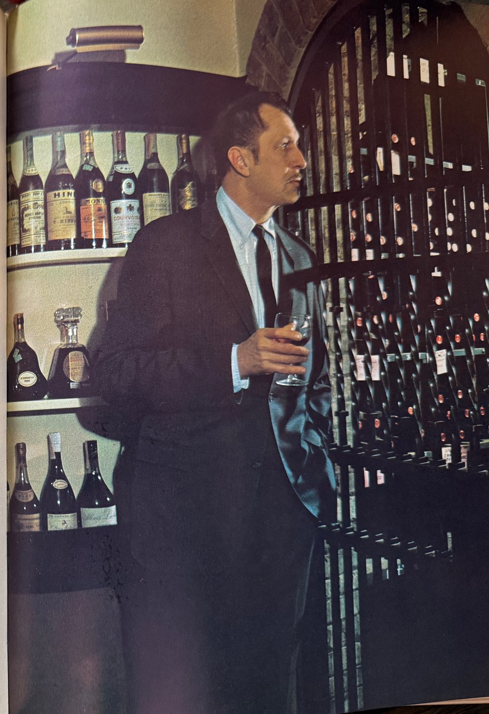 actor Vincent Price holding a glass of brandy in wine cellar in book A Treasury of Great Recipes