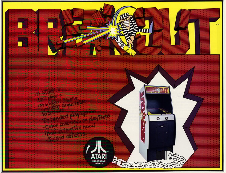You see an arcade cabinet of the videogame "Breakout" that is tied to a chain and ball. Behind it is a red brick wall and the lettering of the word "BREAKOUT".