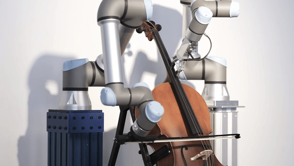 A cello is being played by two robots. The robot on the left holds a bow across the strings, while the robot on the right presses two robotic fingers against the strings on the neck. The robots are made of slender chrome and Gray tubes
