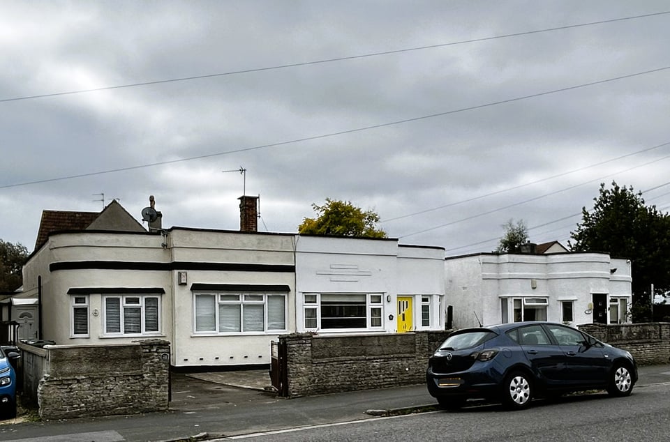 Single storey buildings. Each has one corner slightly stepped back. Each has a different motif along its top. One has the same original 1930s door.