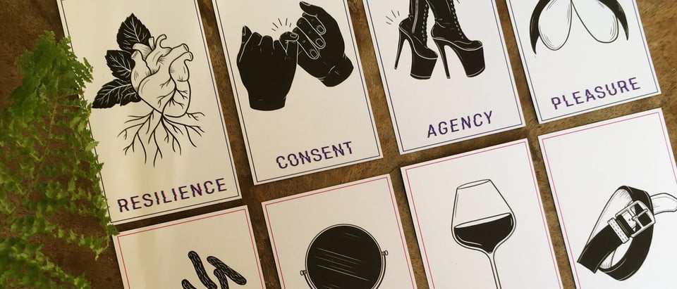 A series of illustrated tarot-like cards on a desk. Text on the card reads: Resilience, Consent, Agency, Pleasure.