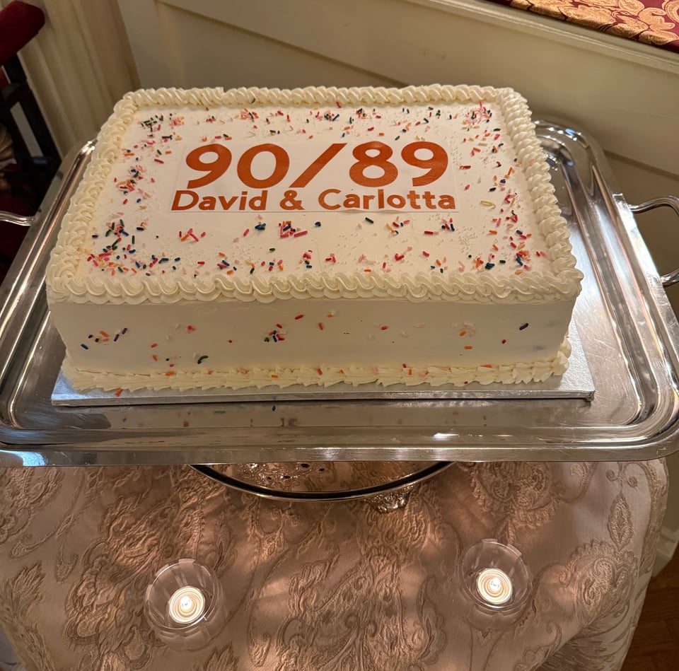 Rectangular white frosted cake decorated with "90/89 David & Carlotta" in celebration of David and Carlotta Schuster's 90 & 89th birthday, at the Lotos Club, NYC