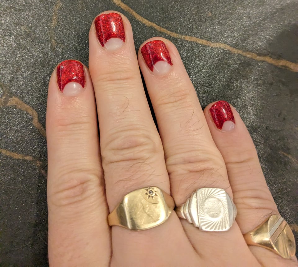 A hand with a glittery red manicure.