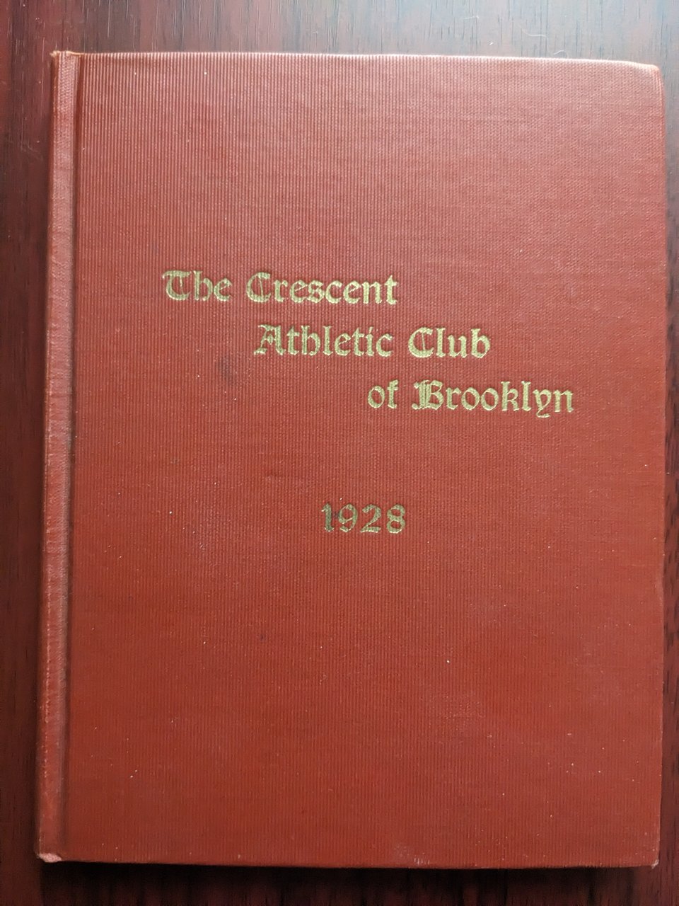 A red book cover with gold Gothic text reading "the Crescent Athletic Club of Brooklyn, 1928."