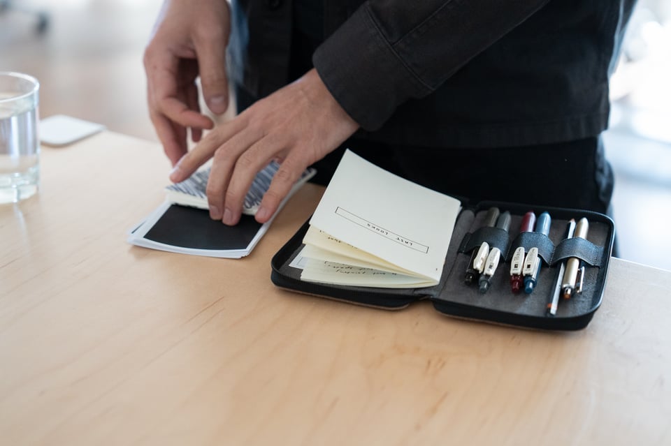 Closeup of hands: A man opens a notebook and arranges some papers.