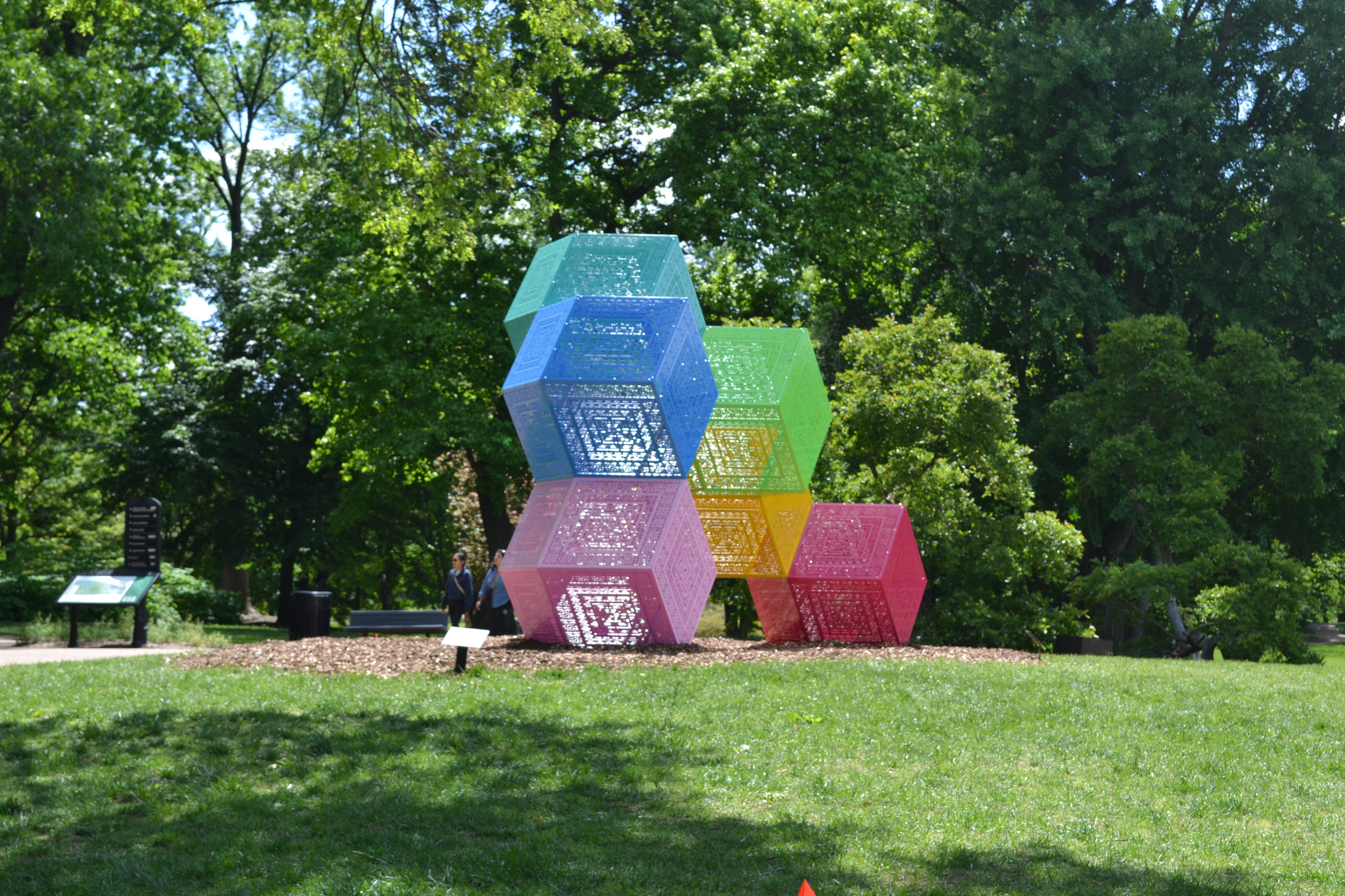 A sculpture of multi-colored polyhedrons - blue, pink, teal, green, yellow, and red, stacked on each other.