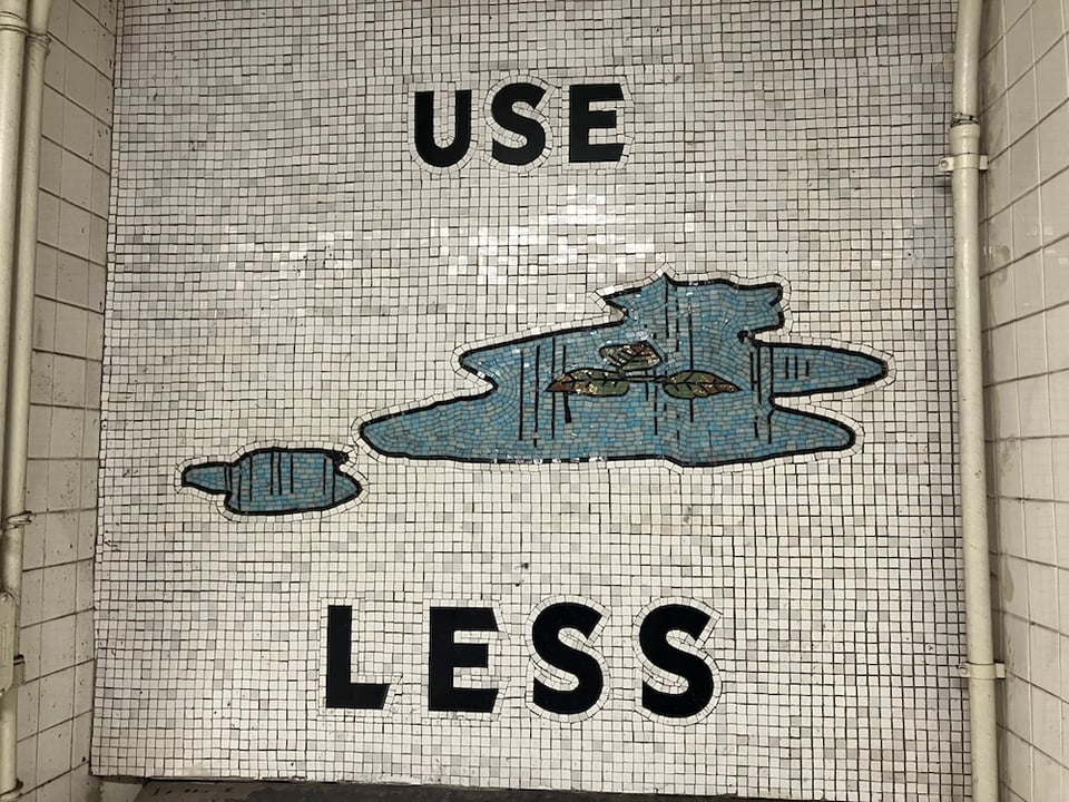 Subway tile mosaic showing a puddle of water bracketed by the text "USE LESS"