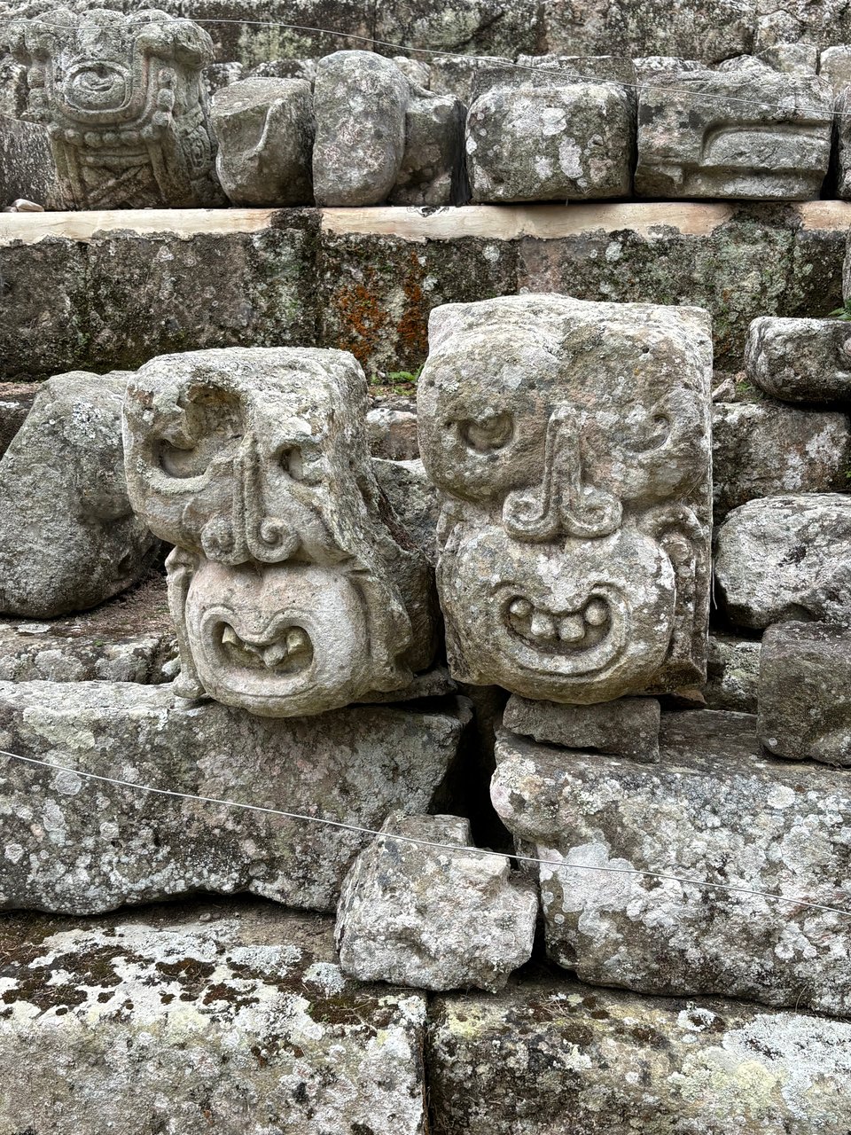 Two stone sculptures of smiling monkey heads, side by side
