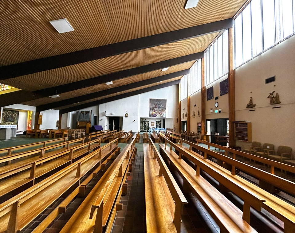 A wide shot of the church interior, showing the scale of the sloping ceiling, western wall of glass and huge beams.