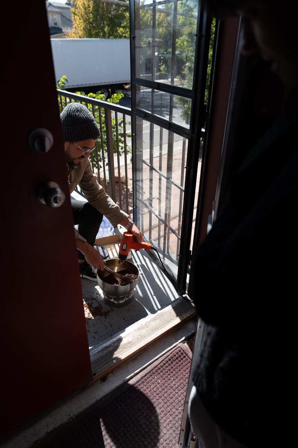 Justin hand-roasting coffee beans on a porch.