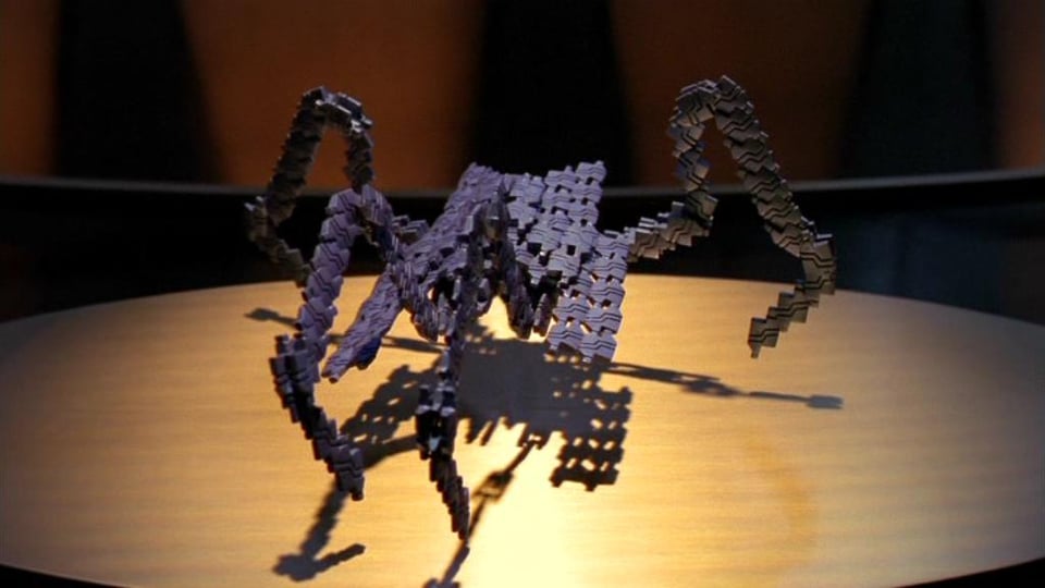 Still image of a machine Replicator from Stargate SG-1, consisting of a spider-looking creature made out of individual metal components that look a whole lot like Legos.