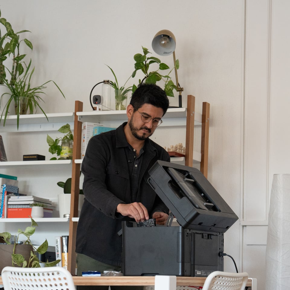 A man helplessly trying to fix a printer.