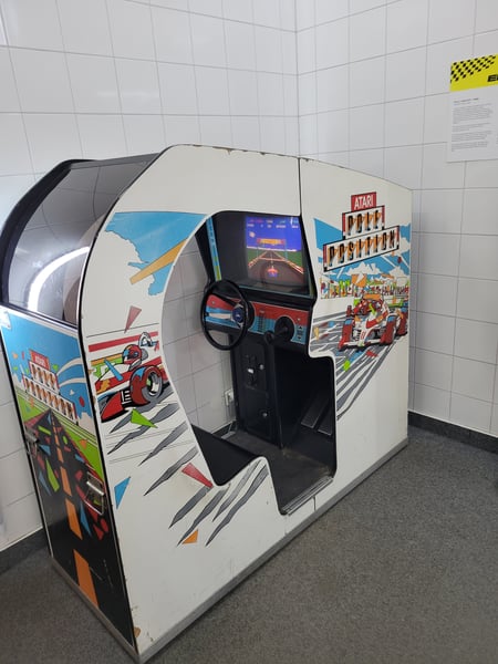 A Pole Position arcade game, which is a covered chair with a steering wheel, gearshift, and pedals.