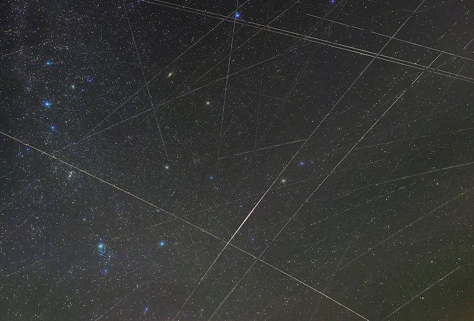 Photo of the night sky with several satellite tracks obscuring the stars.